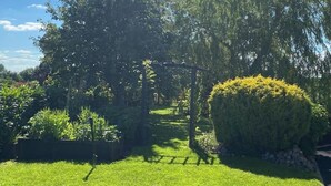 A well-maintained garden with a wooden pergola, lush greenery, and a neatly trimmed bush. - Adorable Cabin in the Countryside (Mountrath)