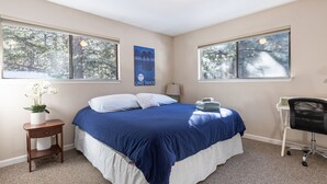 A bedroom with a bed, two windows, a nightstand, a chair, and a poster on the wall. - Enjoy a Cottage near the lake 2bdr, Tahoe 2Bdr Postmasters Cottage (South Lake Tahoe)
