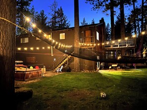 Une maison avec une terrasse, un hamac et des guirlandes lumineuses.