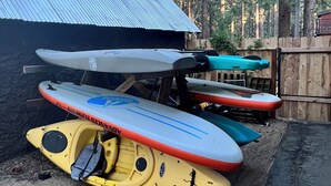 A covered outdoor area with kayaks and a paddleboard leaning against a metal roof. - Enjoy a Cottage near the lake 2bdr, Tahoe 2Bdr Postmasters Cottage (South Lake Tahoe)