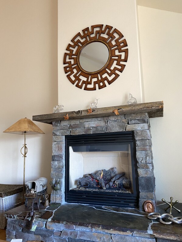 A stone fireplace with a decorative mirror above it, surrounded by rustic decor. - Montana ranch house sunrise sunset views & fields (Bozeman)