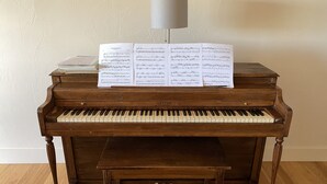 A grand piano with sheet music on top, a bench in front, and a lamp above. - Montana ranch house sunrise sunset views & fields (Bozeman)