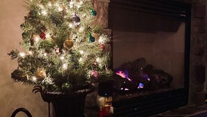 A Christmas tree with ornaments and lights, a fireplace, and wrapped gifts on a mantel. - Montana ranch house sunrise sunset views & fields (Bozeman)