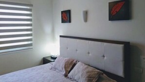 A bedroom with a bed, a nightstand, a ceiling fan, and two wall-mounted artworks. - CONDO BELLA BY TRVL2HM (Puerto Vallarta)