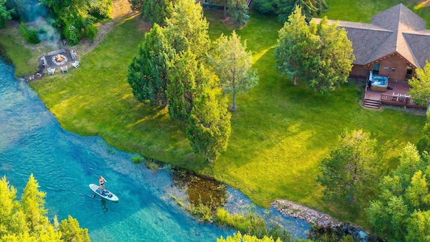 An aerial view of a lodge with a fire pit, outdoor seating, and a dock for paddleboarding. - Private Island, FirePit, HotTub, Arcade, AC, Dogs! (Rigby)