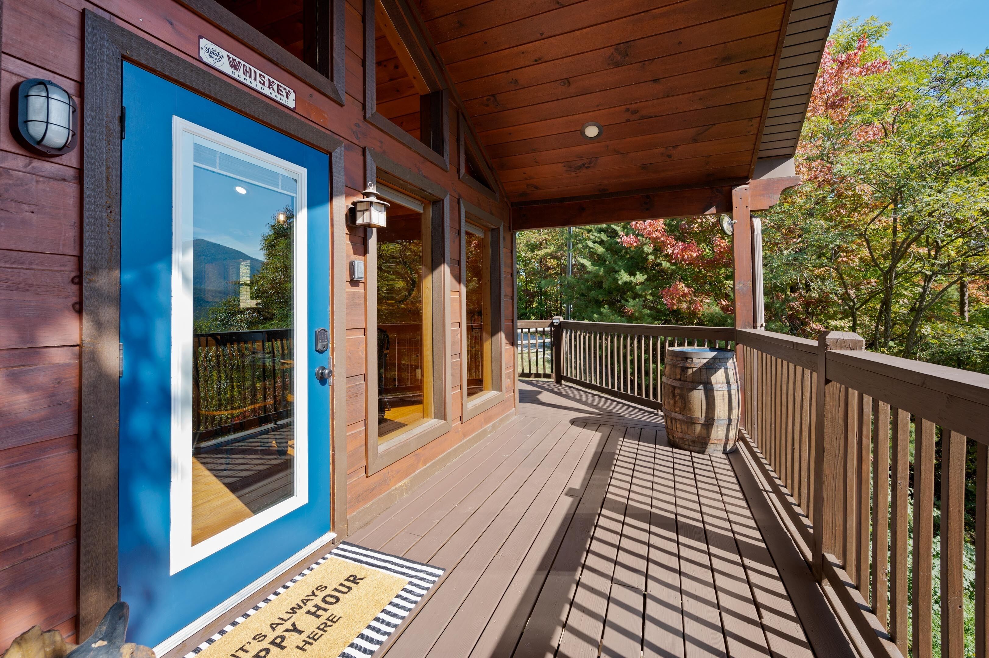 A wooden porch with a blue door, a mailbox, and a doormat.