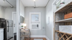 A compact kitchen with a refrigerator, sink, and window with blinds.