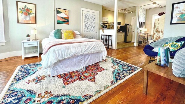 A bedroom with a bed, a desk, and a chair. There is a ceiling fan and a window.