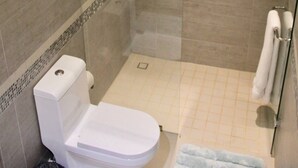 A bathroom with a toilet, a glass-enclosed shower, and a tiled floor. - CONDO L268  BY TRVL2HM (Puerto Vallarta)