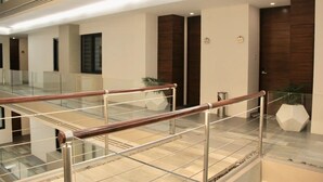 A modern hotel lobby with a glass railing, a wooden door, and a potted plant. - CONDO L268  BY TRVL2HM (Puerto Vallarta)