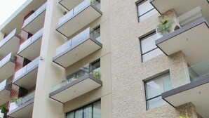 A multi-story building with balconies, a stone facade, and a sign with large letters. - CONDO L268  BY TRVL2HM (Puerto Vallarta)