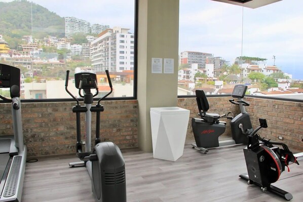 A gym with two stationary bikes, a treadmill, and a white podium.