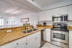 A modern kitchen with granite countertops, stainless steel appliances, and white cabinetry.