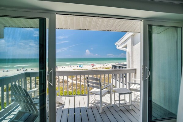 A balcony with a view of the beach and ocean.