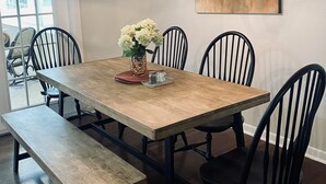 A dining area with a wooden table, black chairs, a bench, a vase with flowers, a painting on the wall, and a hanging light fixture. - Private Retreat with your dogs: close to WEC (Ocala)