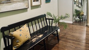 A hallway with a wooden bench, framed artwork on the walls, and a mirror reflecting the room. - Private Retreat with your dogs: close to WEC (Ocala)
