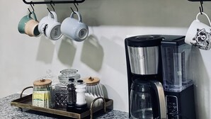 A kitchen counter with a coffee maker, a framed painting, and a hanging light fixture. - Private Retreat with your dogs: close to WEC (Ocala)