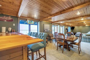 A restaurant with wooden ceiling beams, a bar area, and a dining section with upholstered chairs and tables.