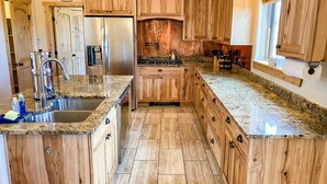 Eine Küche mit Holzausstattung, Edelstahlgeräten, Granitarbeitsplatten und gefliestem Boden.