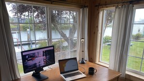 A wooden desk with a desktop computer and a laptop, a black lamp, and a black mug.