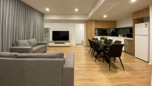 Un salon moderne comprenant un canapé, un téléviseur et un coin repas avec des chaises et une table.