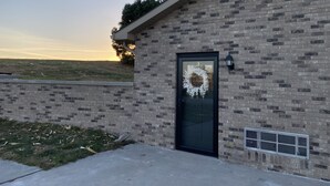 A brick building with a black door, a wreath on the door, and a small window with a light fixture. - Quiet rural home located 2 miles from downtown Milford (Milford)