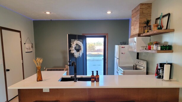 A kitchen with a central island, bar stools, a refrigerator, a microwave, and a coffee maker. - Quiet rural home located 2 miles from downtown Milford (Milford)