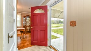 Una puerta roja que da a un comedor con una mesa y sillas de madera.