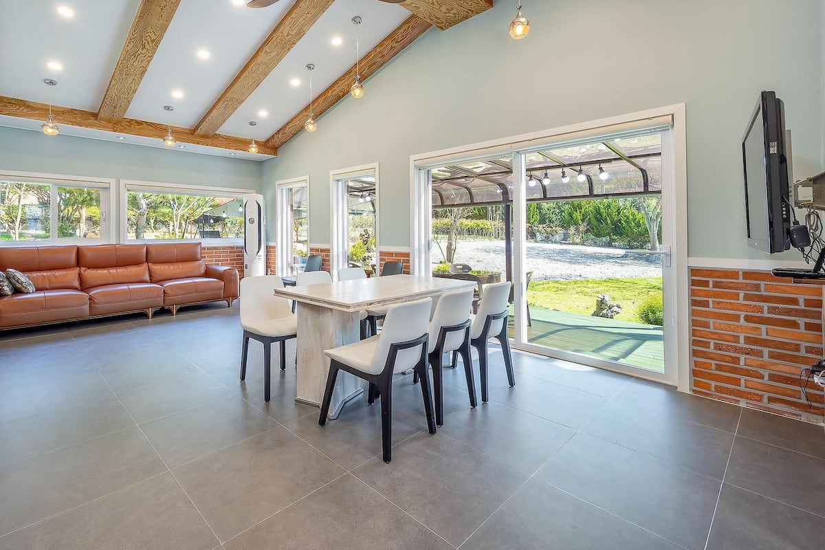 Amplia habitación con una gran mesa de comedor, un sofá de cuero y vistas al exterior.