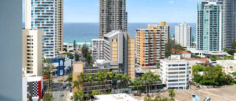 A cityscape with high-rise buildings, a road, and palm trees.