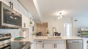 Une cuisine moderne dotée d’appareils électroménagers en acier inoxydable, de meubles blancs et d’un îlot central avec un évier.