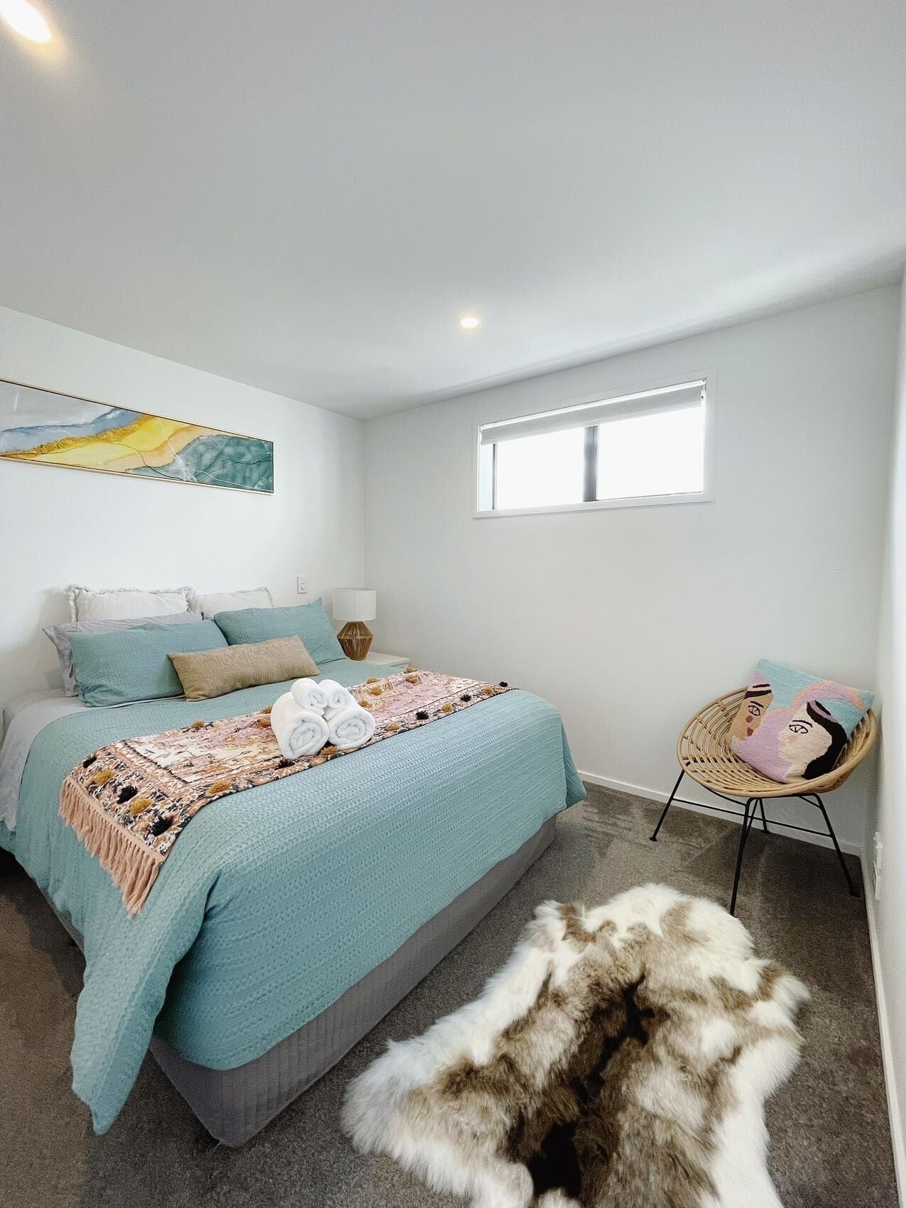 A bedroom with a bed, a chair, a rug, and a window.