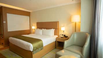 Una habitación de hotel con cama, una silla, una mesita de noche y una lámpara.