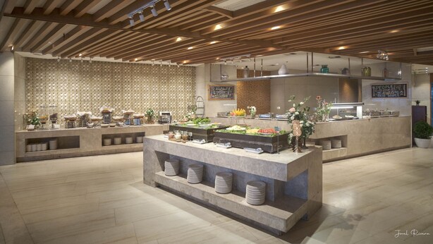 A modern buffet setup with a variety of food items, a wooden ceiling design, and a patterned wall in the background. - Ion Hotel (Baguio)