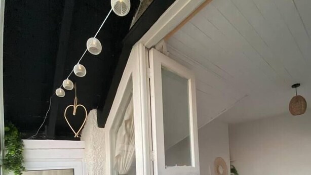 Un dormitorio con una cama, una silla de mimbre y una ventana con cortinas.