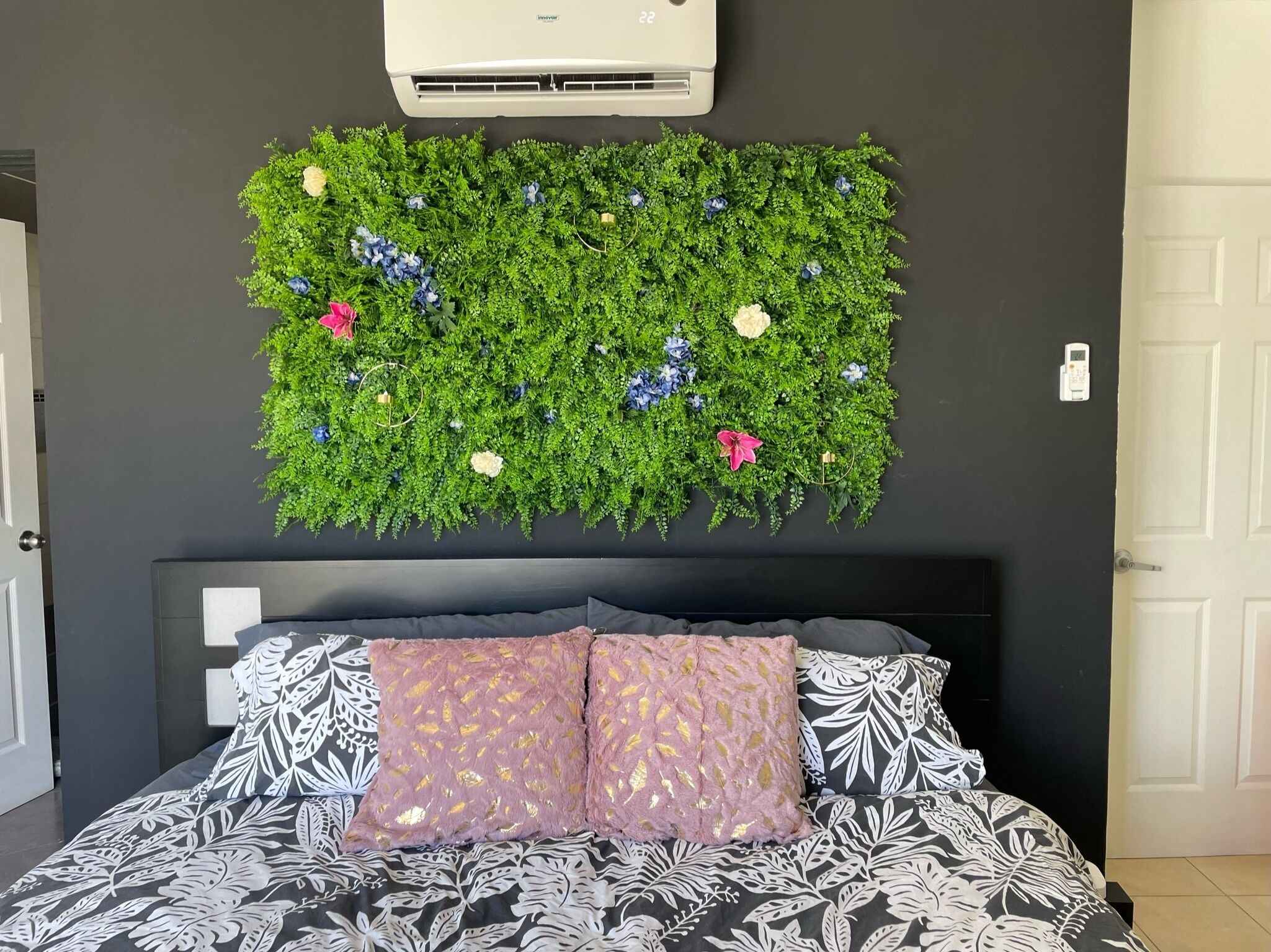 Une chambre à coucher comprenant un lit, un climatiseur fixé au mur et un élément décoratif mural.