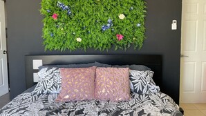 A bedroom with a bed, a wall-mounted air conditioner, and a decorative wall hanging. - *NEW* Casita Lalita -  2bd/2.5 ba condo - 5 mins to beach w/ 200mbps wifi + pool (Tamarindo)