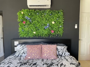 A bedroom with a bed, a wall-mounted air conditioner, and a decorative wall hanging. - *NEW* Casita Lalita -  2bd/2.5 ba condo - 5 mins to beach w/ 200mbps wifi + pool (Tamarindo)