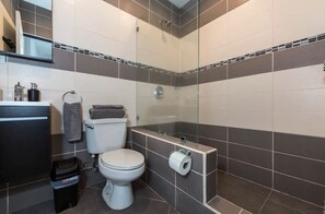 Un baño moderno con inodoro, lavamanos y ducha.