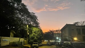 A street at dusk with parked cars, a building with a sign reading "CASA DEBEACH", and trees lining the road. - *NEW* Casita Lalita -  2bd/2.5 ba condo - 5 mins to beach w/ 200mbps wifi + pool (Tamarindo)