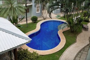 Una piscina de diseño curvo, rodeada de palmeras y un césped bien cuidado.
