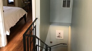 Una scala con gradini in legno e ringhiere nere che porta a un pianerottolo.