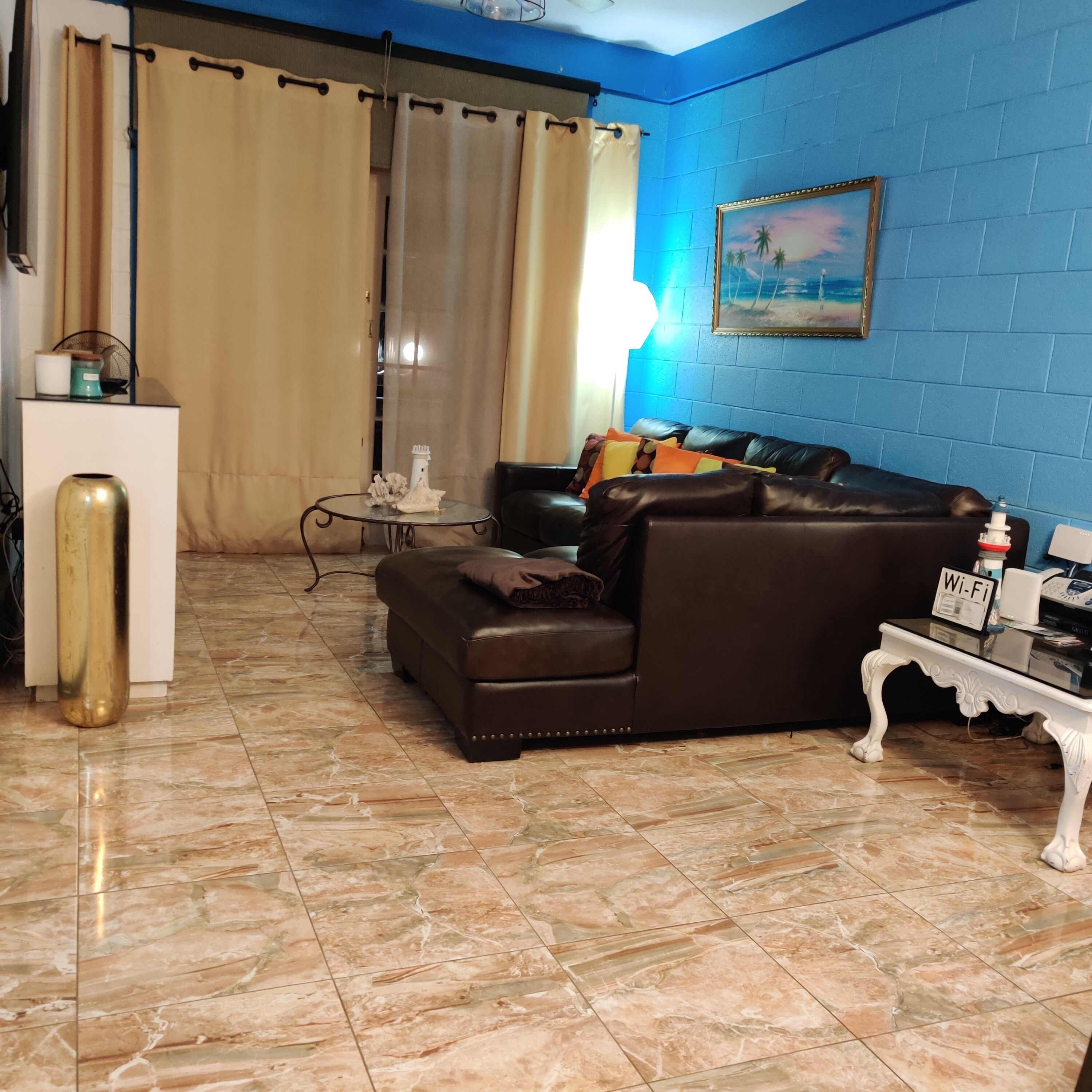 A living room with a brown leather sofa, a glass coffee table, and a white side table with a Wi-Fi sign.