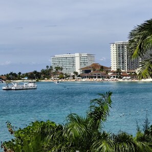 A coastal hotel with a large building, a beach, and a boat on the water.