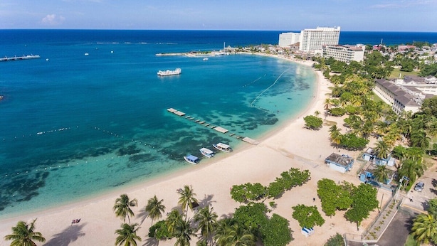 A coastal resort with a beach, clear waters, and a pier.