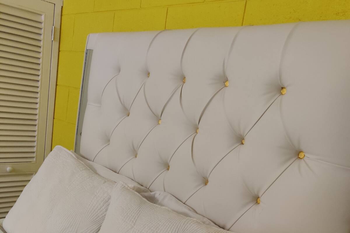 A bed with a tufted headboard, a folded teal blanket, and a white pillow.