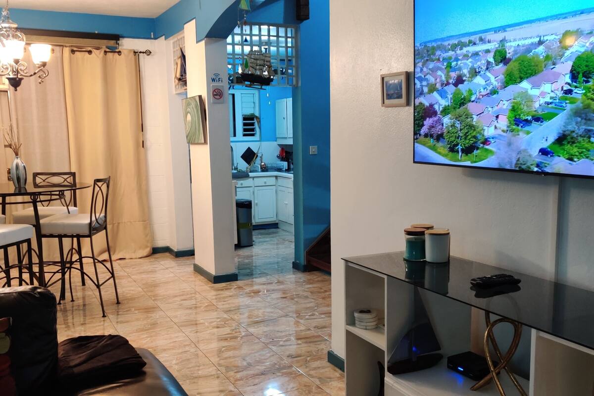 A living room with a TV, a dining area, and a kitchen.