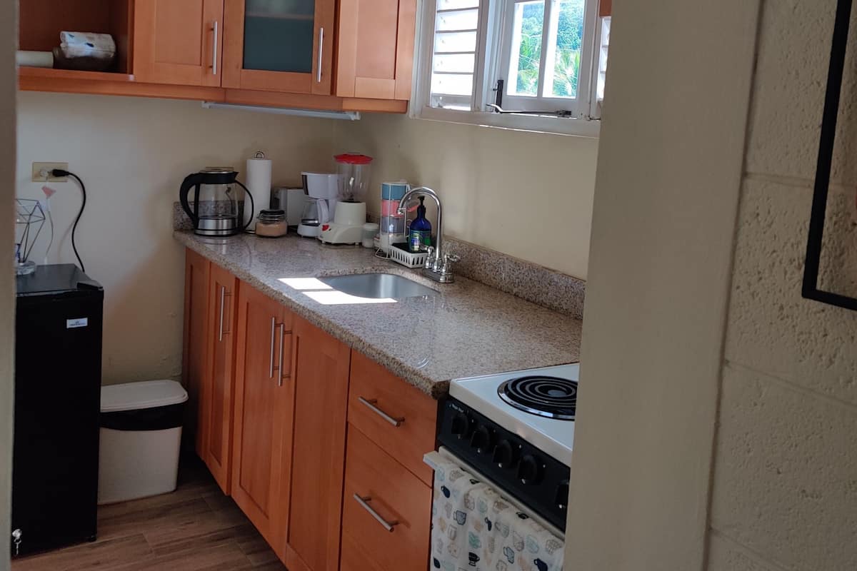 A kitchen with wooden cabinets, a sink, a stove, and a window with blinds.