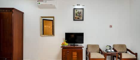 A living room with a TV, two chairs, a cabinet, and a framed mirror.