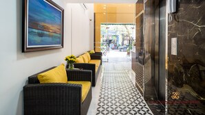A reception area with a sofa, a painting, and a patterned floor. - LILA Hotel & Apartments (Ho Chi Minh City)